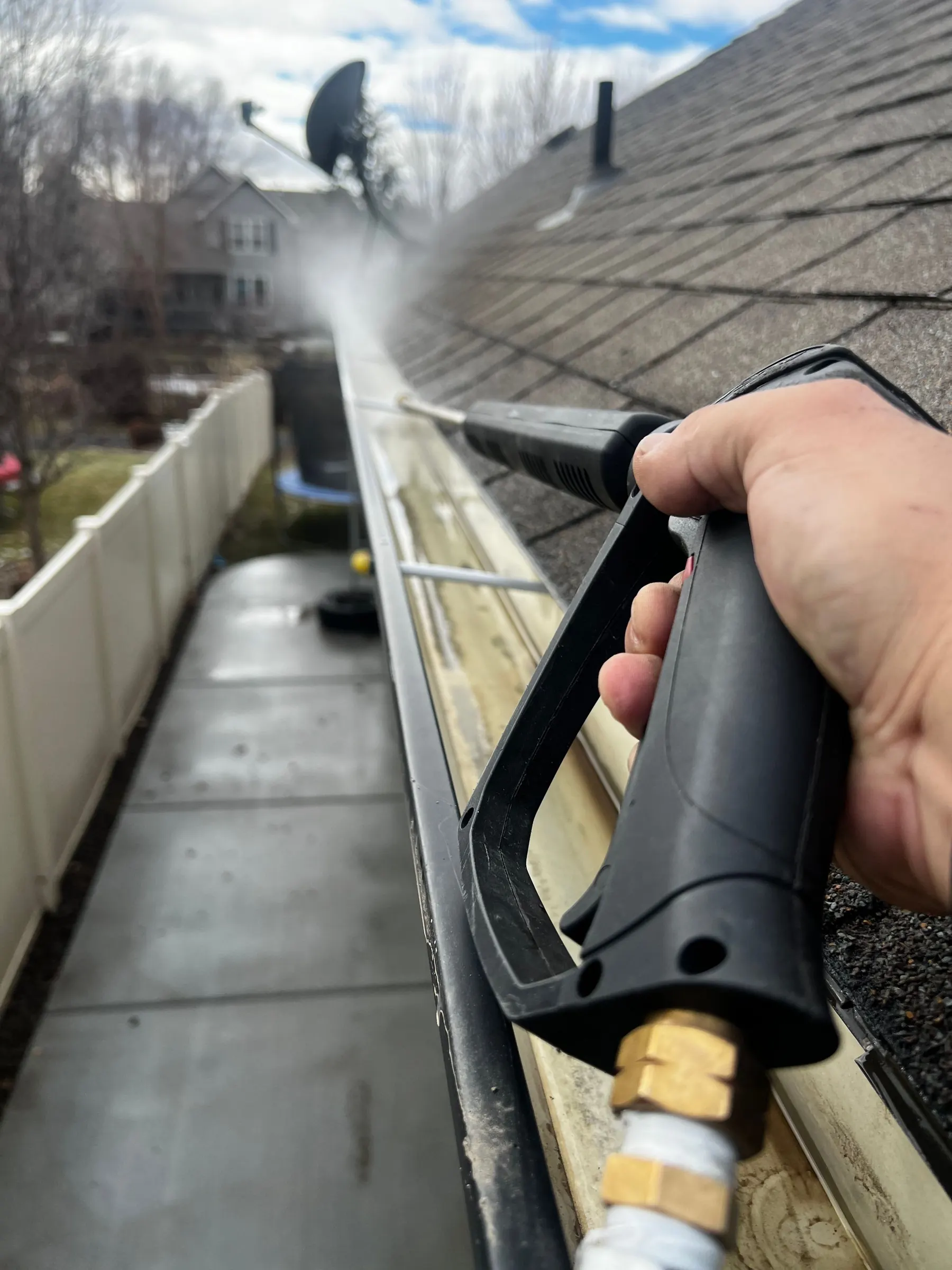 Power washer cleaning out a house gutter